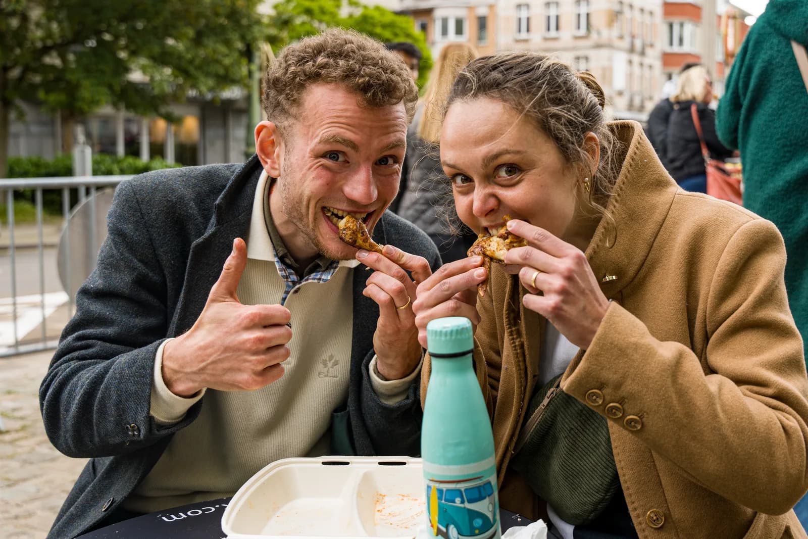 Un couple mange de la street food en riant.